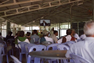 a room full of people watching a televised trial