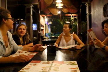 four women looking at menus, seated around a table in a restaurant