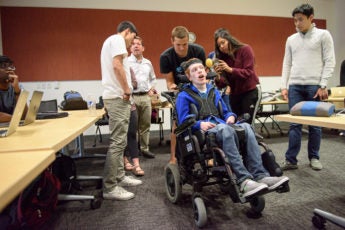 Students in the Compassionate Design class taught by John Moalli take photos of the wheelchair used by Zach Crighton, a 17-year-old high school student with cerebral palsy. The students are hoping they can make improvements to his wheelchair and communications tools.