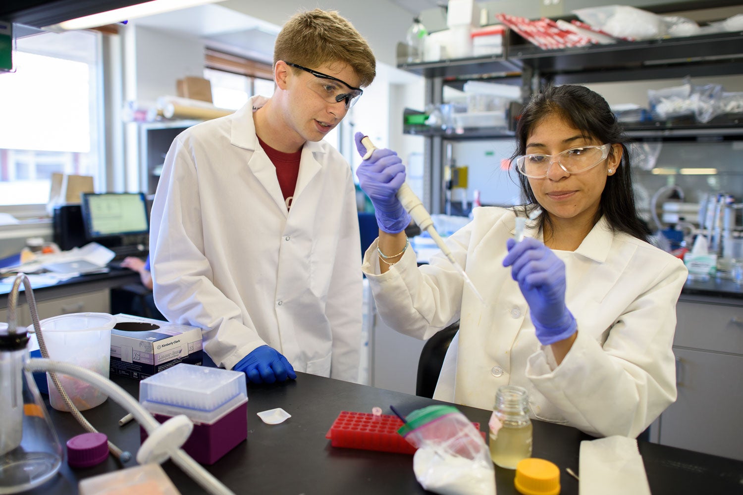 Chris Lindsay, left, a doctoral candidate in materials science, works one-on-one with Blanca Jaime, a high school student, in a laboratory.