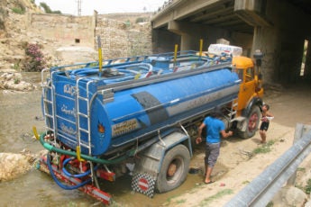 A tanker truck illegally takes water from a river in Jordan.