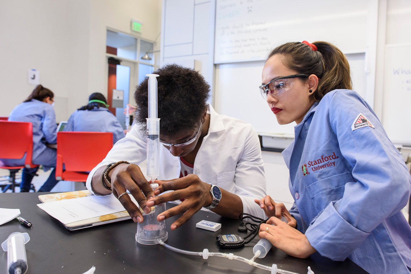 John Okhiulu and Bao Phan work together to test how different gases affect a lighted candle.