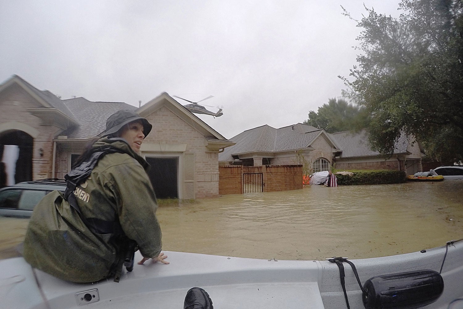 Neighborhood under water with guard in boat in foreground and helicopter flying overhead in background