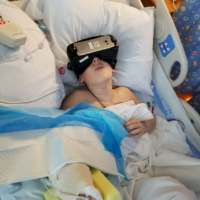 A boy in the hospital wears virtual reality goggles.
