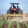 a farmer on a tractor tilling soil