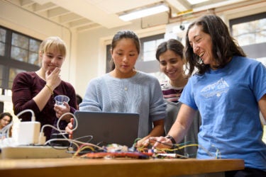 Grad student Laura Blumenschein, left, observes Grace Zhao and Goli Emami's project which gives haptic feedback while navigating a maze. Cara Welker, right, a grad student in bioengineering tests the device.