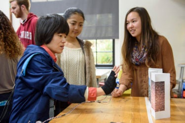 Visiting scholar, Rui Yang, tests the depth sensing glove developed by freshmen Megumi Sano and Kira Jan.