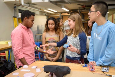 Senior Moses Swai, left, gets a demonstration from Jabreea Johnson, Charlotte Peale, and Johnny Armenta who developed a Foot Haptic device.