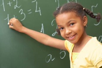 happy girl doing math at chalkboard