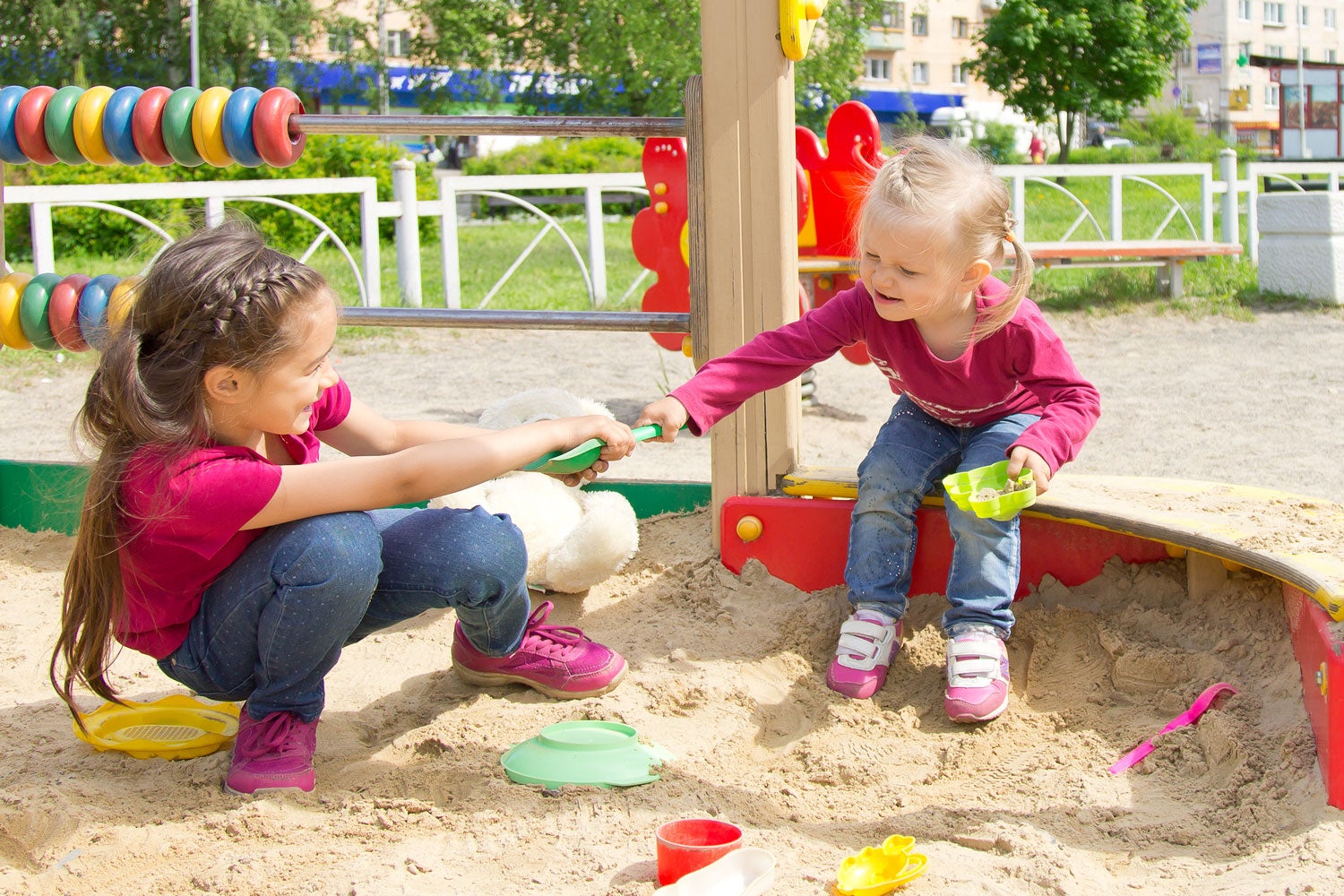 kids squabbling over a toy in a playground sandbox