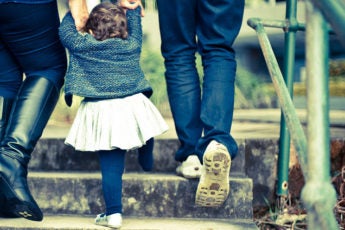 Child holding parents' hands going up stairs