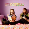 Janet Cartwright sits on a bed with a dog while her daughter reads