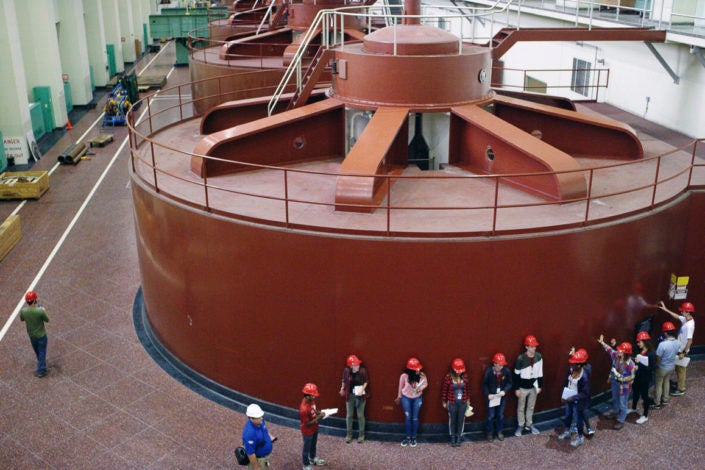 Stanford students stand next to a generator inside a dam)