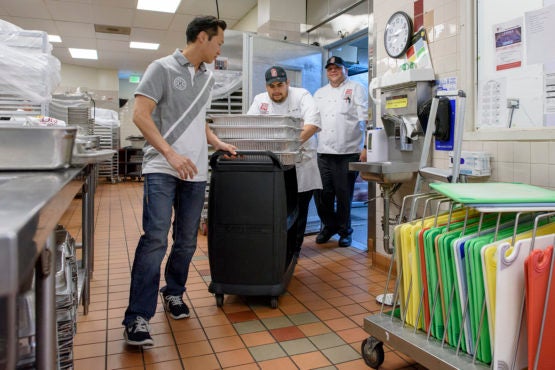 David Ko, Emerson Erazo, Jr. and Jose Diaz bring a cart of food through Stern dining's kitchen