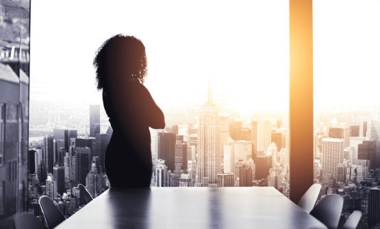 Silhouette of woman standing alone in boardroom