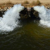 Water gushes from a pipe into a farm irrigation canal in Central California.
