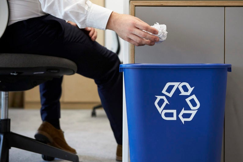 Man dropping paper into recycling bin