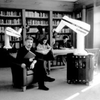 Khatib sitting in a library with two robot arms