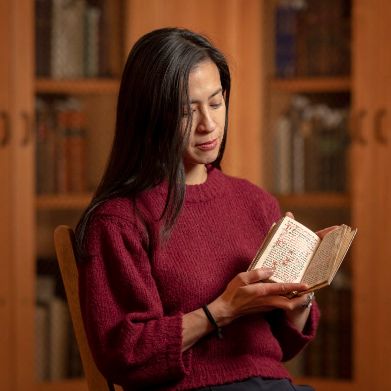 Marisa Galvez holds a contemplative manuscript from the 16th century made for a Franciscan nun