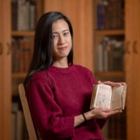 Marisa Galvez, holds a manuscript from Stanford Libraries Special Collections