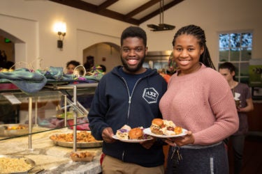 Two students holding plates of food.