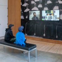 Visitors at Stanford’s Cantor Arts Center absorb the video images from Kahlil Joseph’s BLKNWS, 2018.