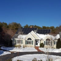 House with solar panels surrounded by snow.