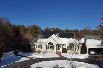 House with solar panels surrounded by snow.