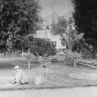 Black and white image of worker in a yard.
