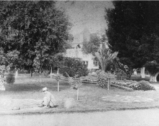 Black and white image of worker in a yard.