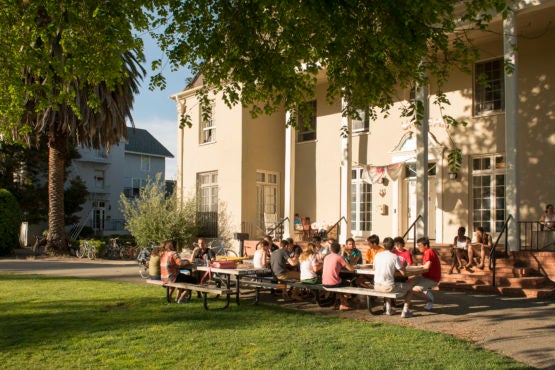 Students sitting at tables outside residence.