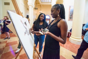 Esther Omode works on a pastel drawing in the rotunda