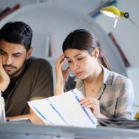 Millennial couple reviewing invoices and looking stressed