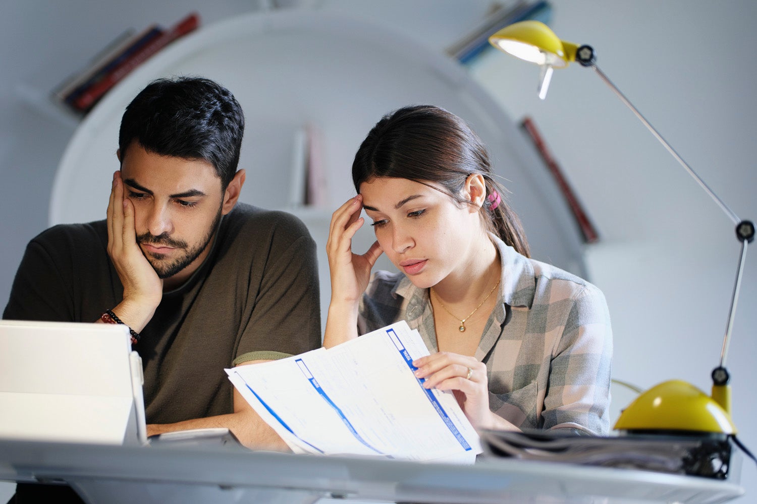 Millennial couple reviewing invoices and looking stressed