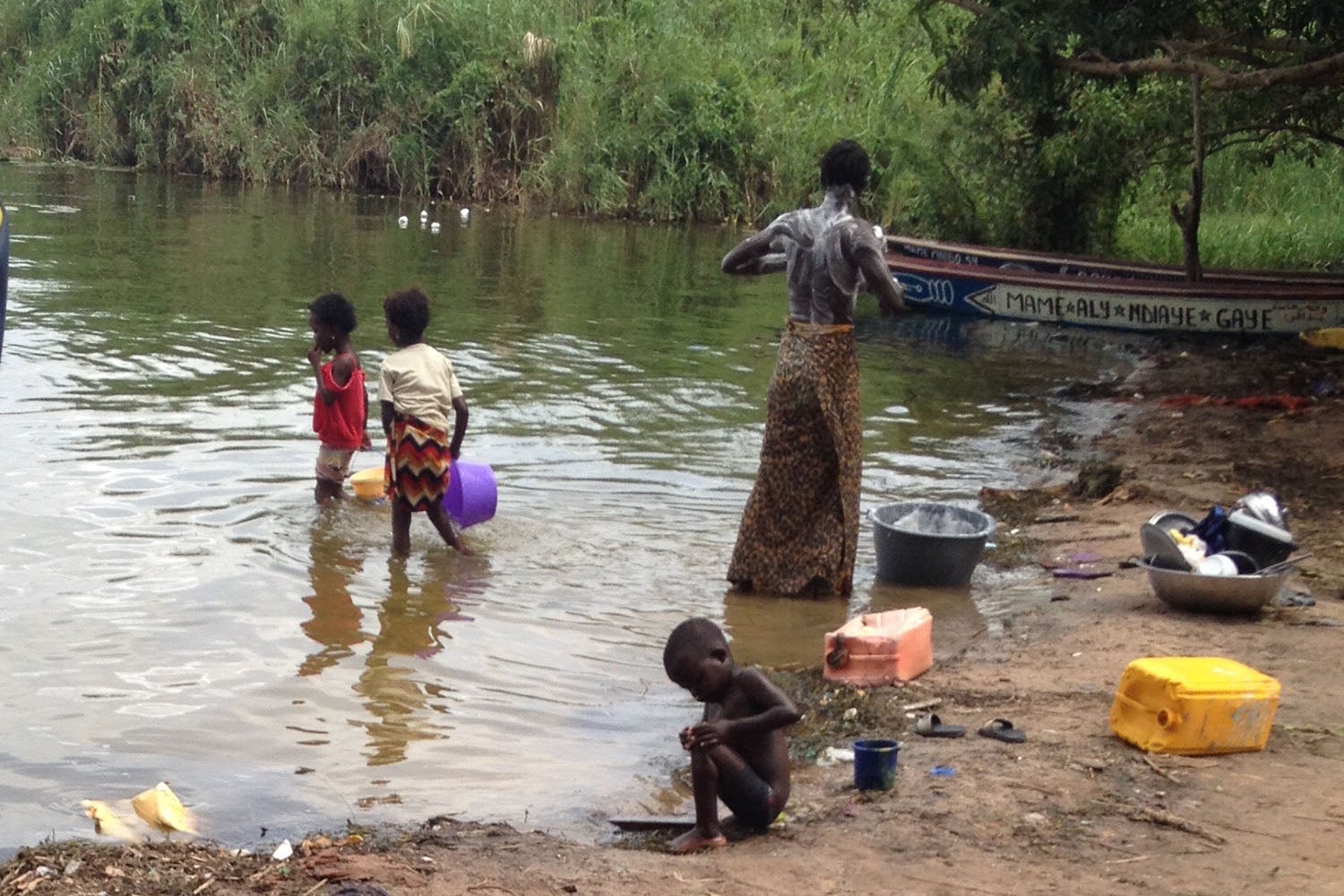 A man bathes in the Senegal River, while children play nearby.