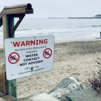 A beach in Half Moon Bay, California, displays a public health warning due to the detection of high concentrations of bacteria in the water.