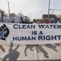 Students walking down a street, holding a banner that says Clean Water is a Human Right