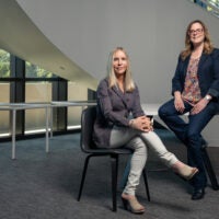 Senior associate vice provosts, Jennifer Cochran and Judith “Jodi” Prochaska pose seated in chairs.