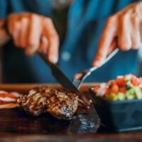 Hands holding fork and knife preparing to eat steak