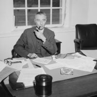 Dr. J. Robert Oppenheimer, suspended Atomic Energy Commission consultant, smokes at his desk at the Princeton Institute for Advanced Study. June 2, 1964.