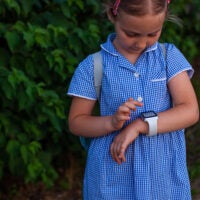 Child looks at smartwatch on her wrist.